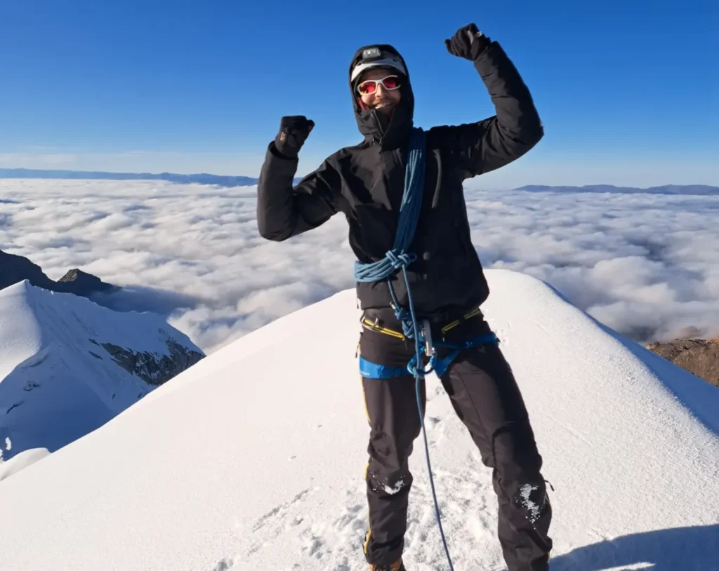 Christopher Sterzik standing triumphantly on a mountain peak with raised fists – symbolizing transformation and personal breakthrough